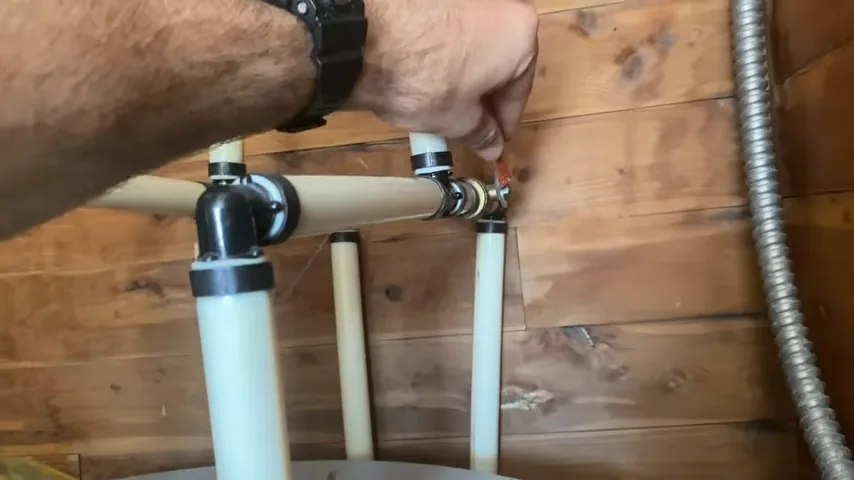 Close-up of a water heater valve and connected pipework beside timber framing